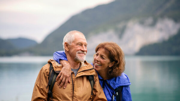 Senior pensioner couple hiking by lake in nature, resting.